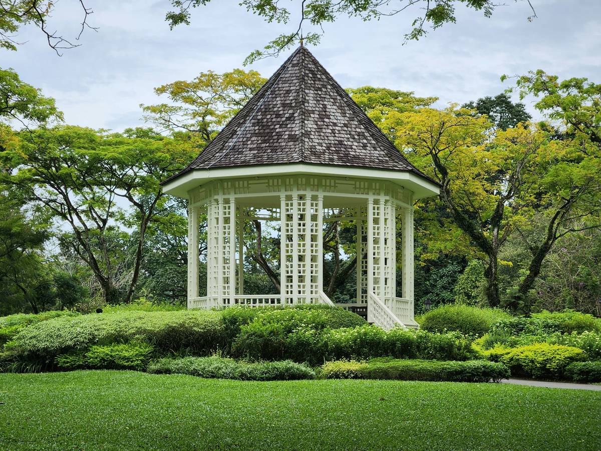 Weathered cedar wooden gazebo for garden with curved bench and hanging lanterns